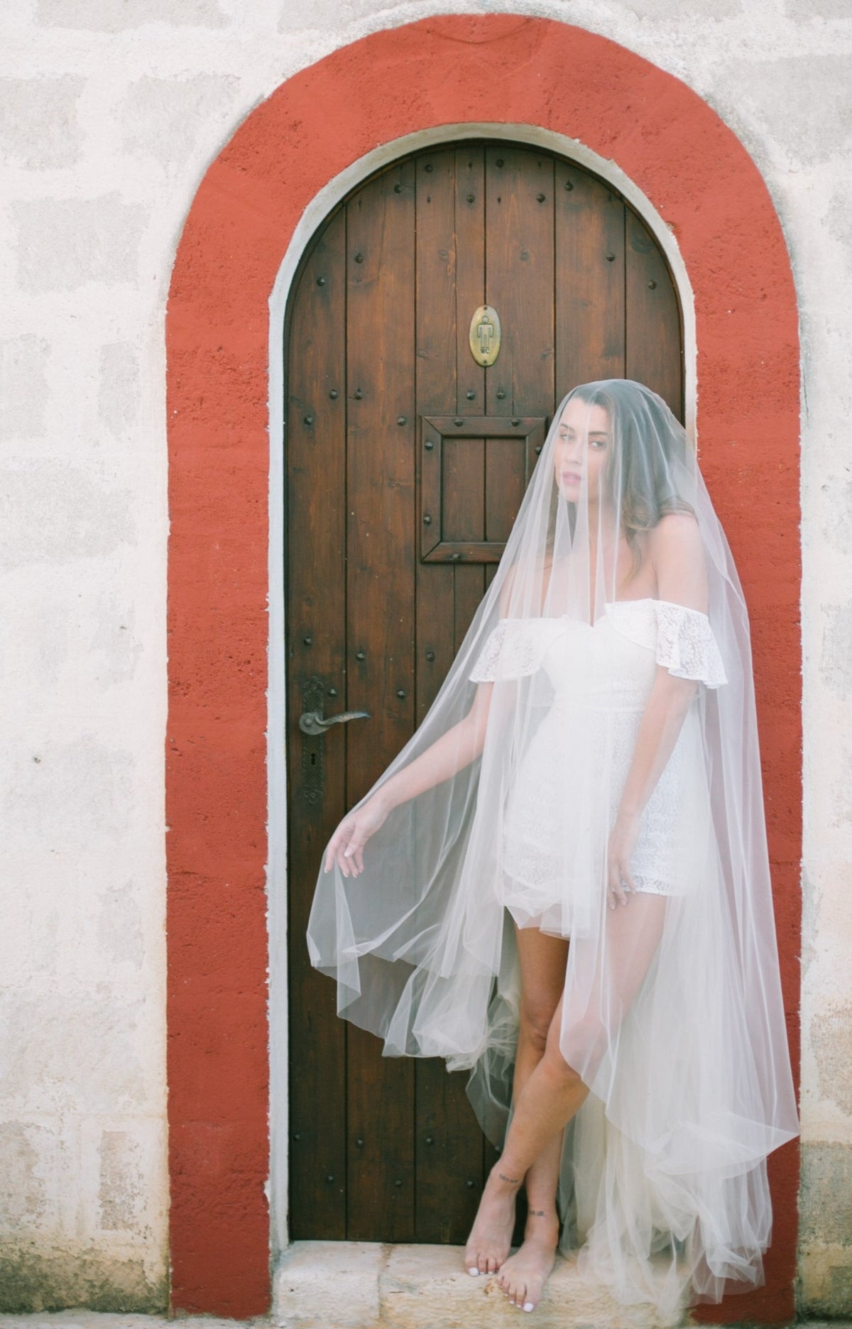 a bride in puglia poses with romantic veil wearing a white wedding lace romper