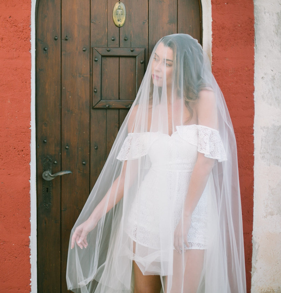 Woman standing in front of a door wearing a strapless bridal jumpsuit