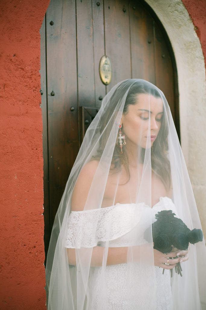 Woman wearing white bridal jumpsuit holding a bouquet of flowers