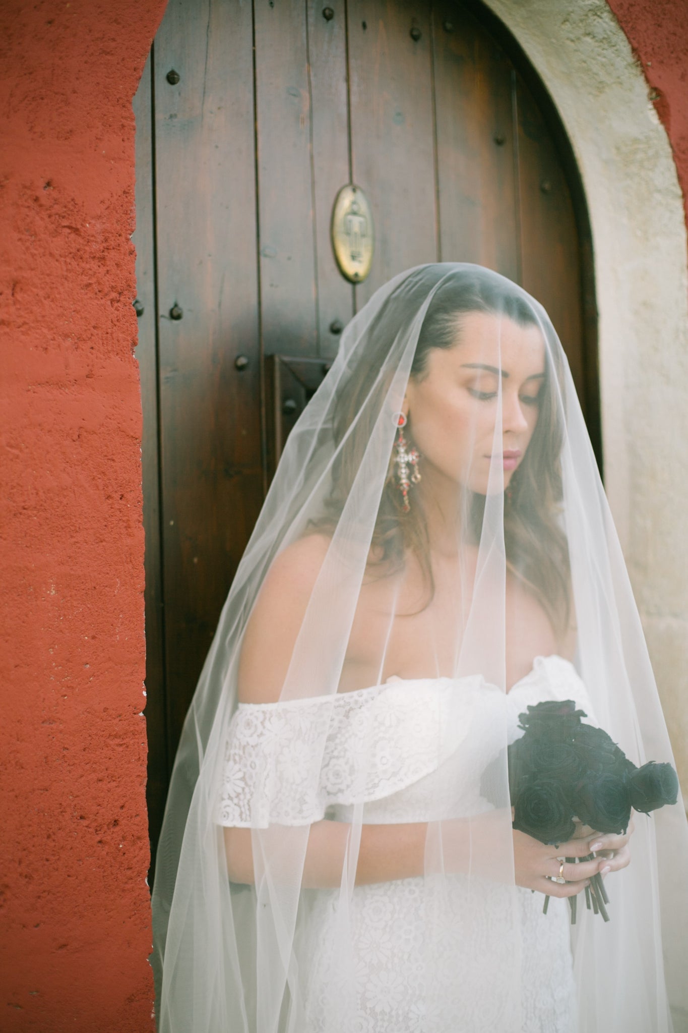 Woman wearing white bridal jumpsuit holding a bouquet of flowers