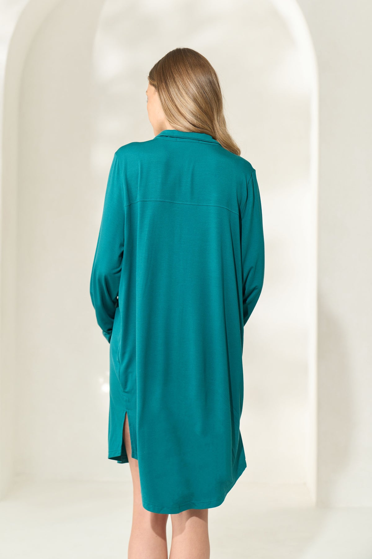 Rear view of woman wearing knee-length juniper green modal boyfriend shirt. 