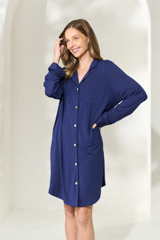 Smiling woman wearing button-up knee-length navy modal boyfriend shirt running her hand through her hair. 