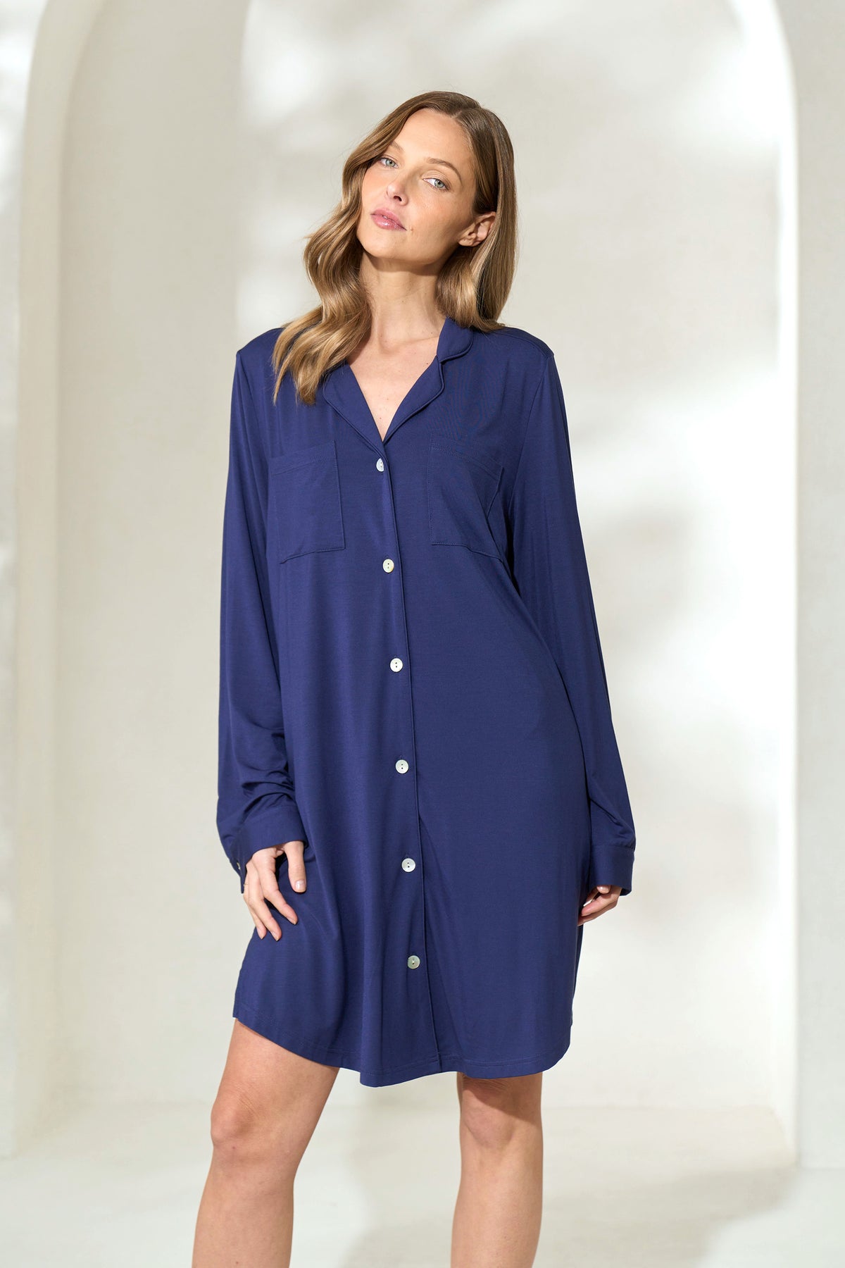 Woman wearing knee-length navy button-up modal boyfriend shirt with long sleeves. 