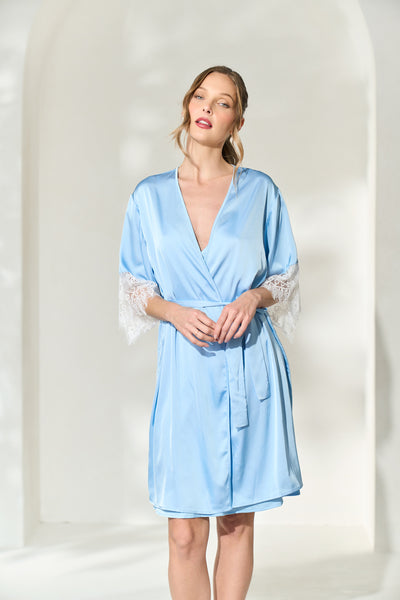 Woman wearing powder blue silky bridal robe with lace trim on the sleeves. 