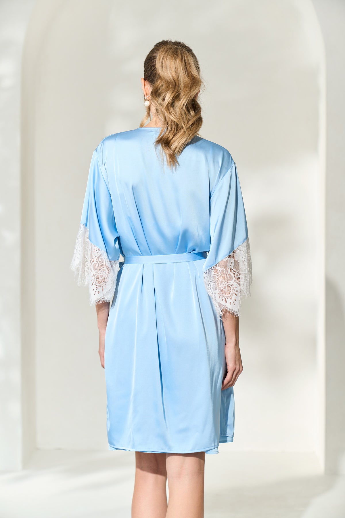 Back view of bride wearing powder blue robe with lace trimmed sleeves