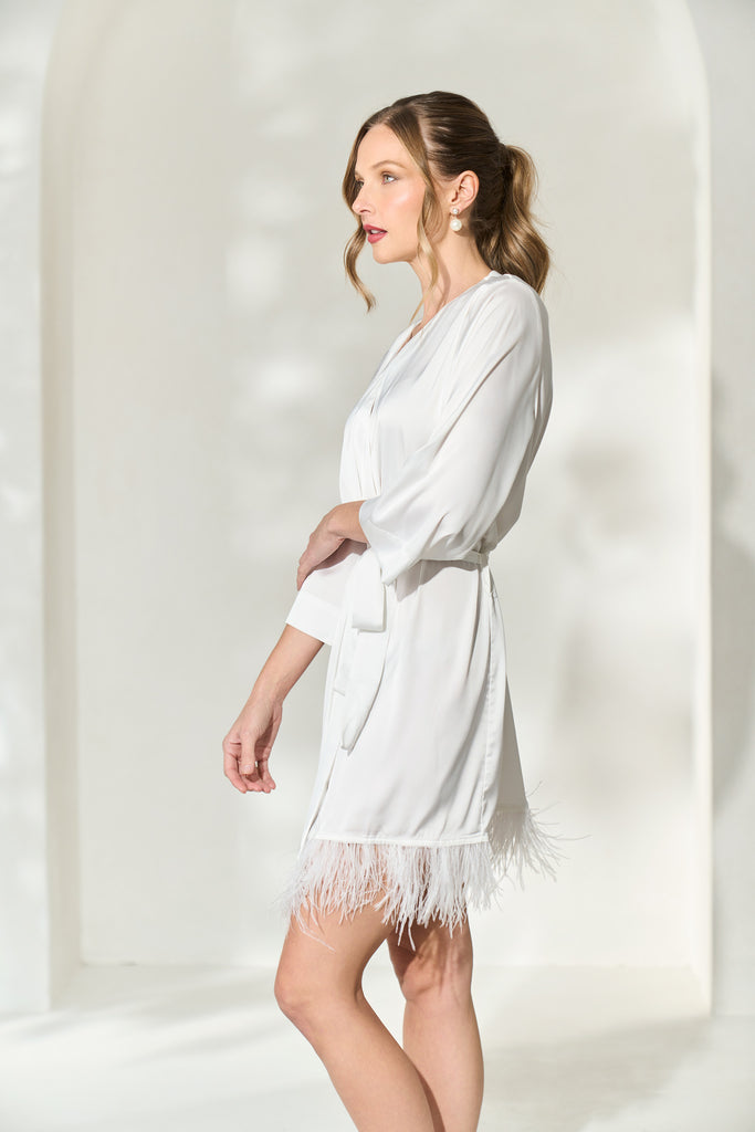 Side view of woman wearing solid white bridal robe with feather trim