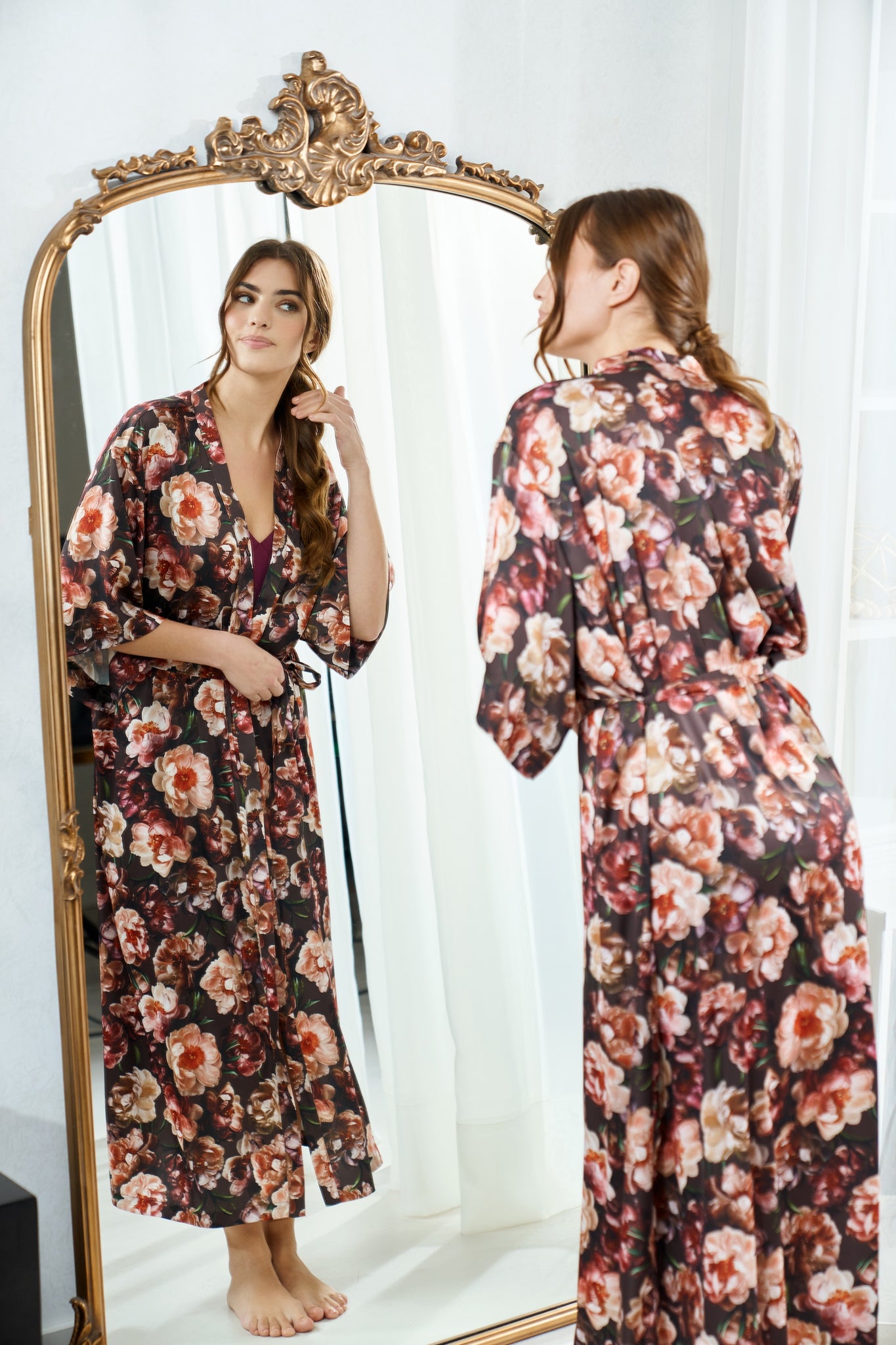 Woman wearing a by catalfo silky floral robe standing in front of a full-length mirror.
