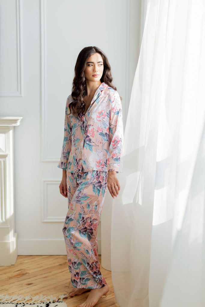 Woman standing beside billowing curtain wearing pink floral print pajama set