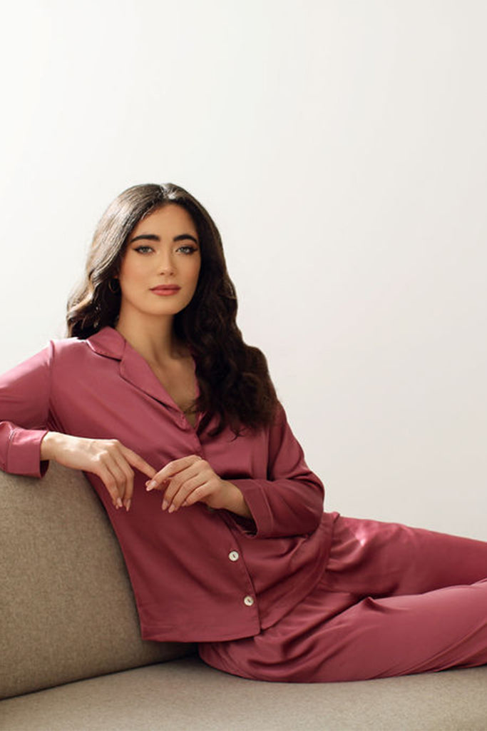 Woman lounging on couch wearing light red pajama set