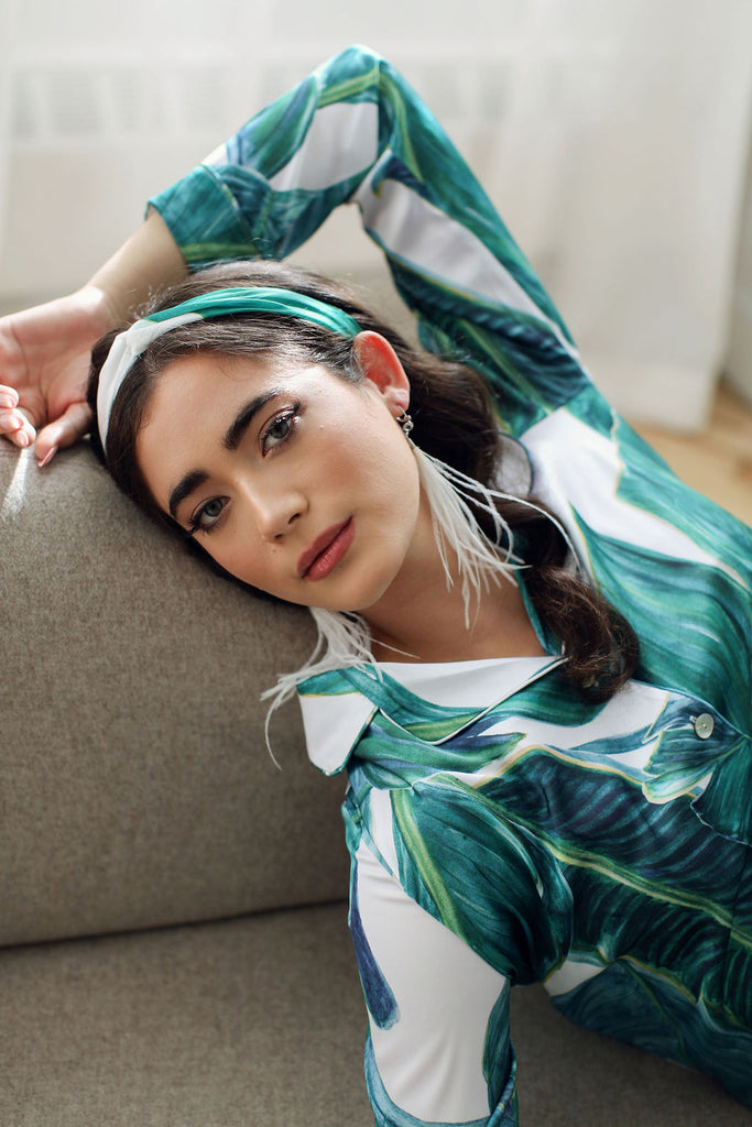 a women lounges in By Catalfo's silky palm print pj's