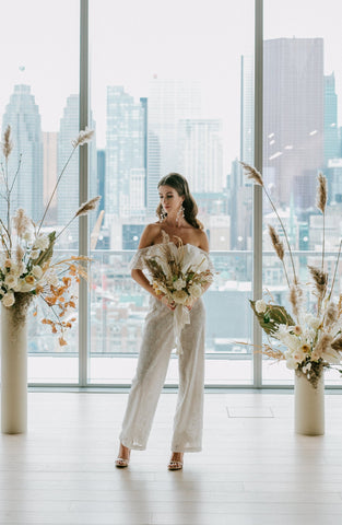 a bride holds a bouquet wearing a white wedding jumpsuit, downtown toronto