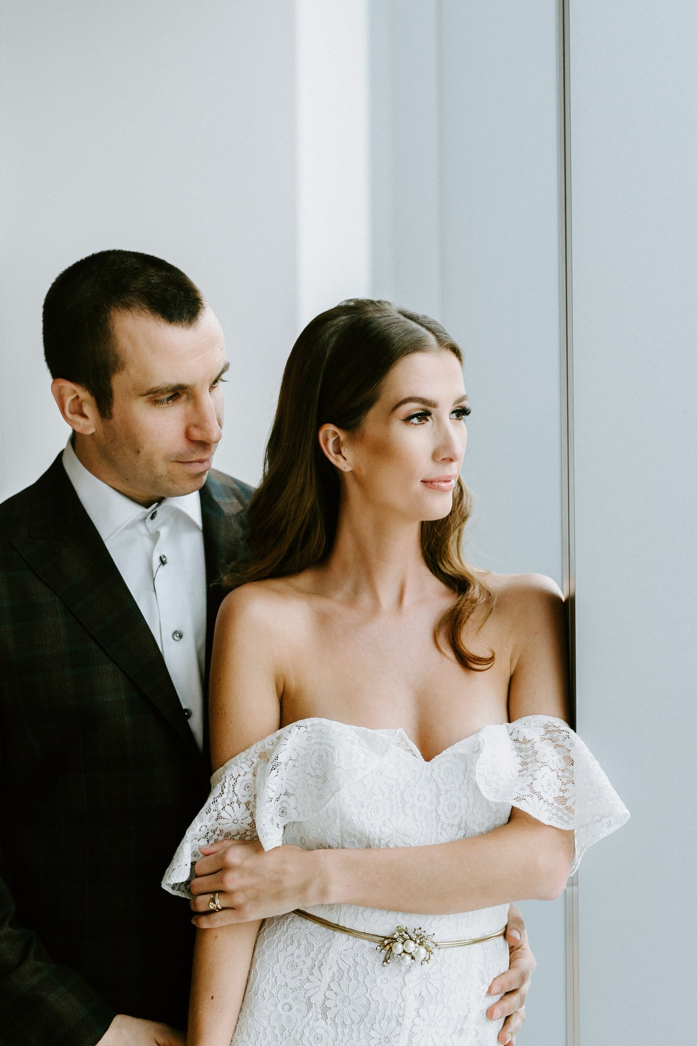 Man looking lovingly at his bride who is wearing a white bridal jumpsuit