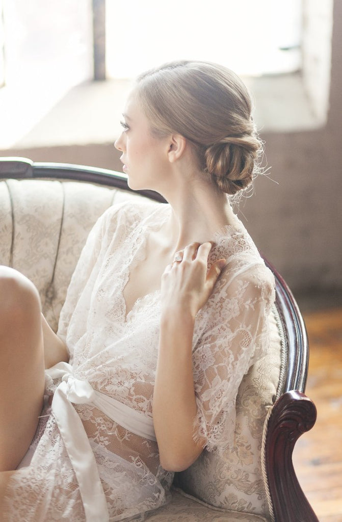 Woman wearing a seductive white lace robe while lounging on a couch