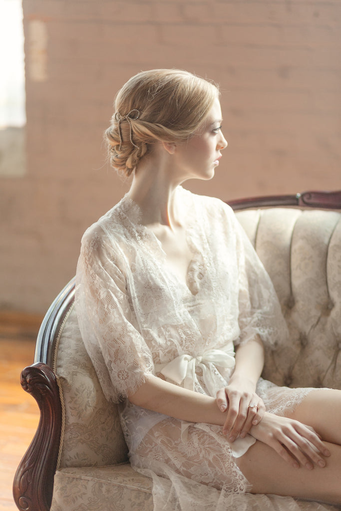 A woman sitting on a couch wearing a sexy lace bridal robe.