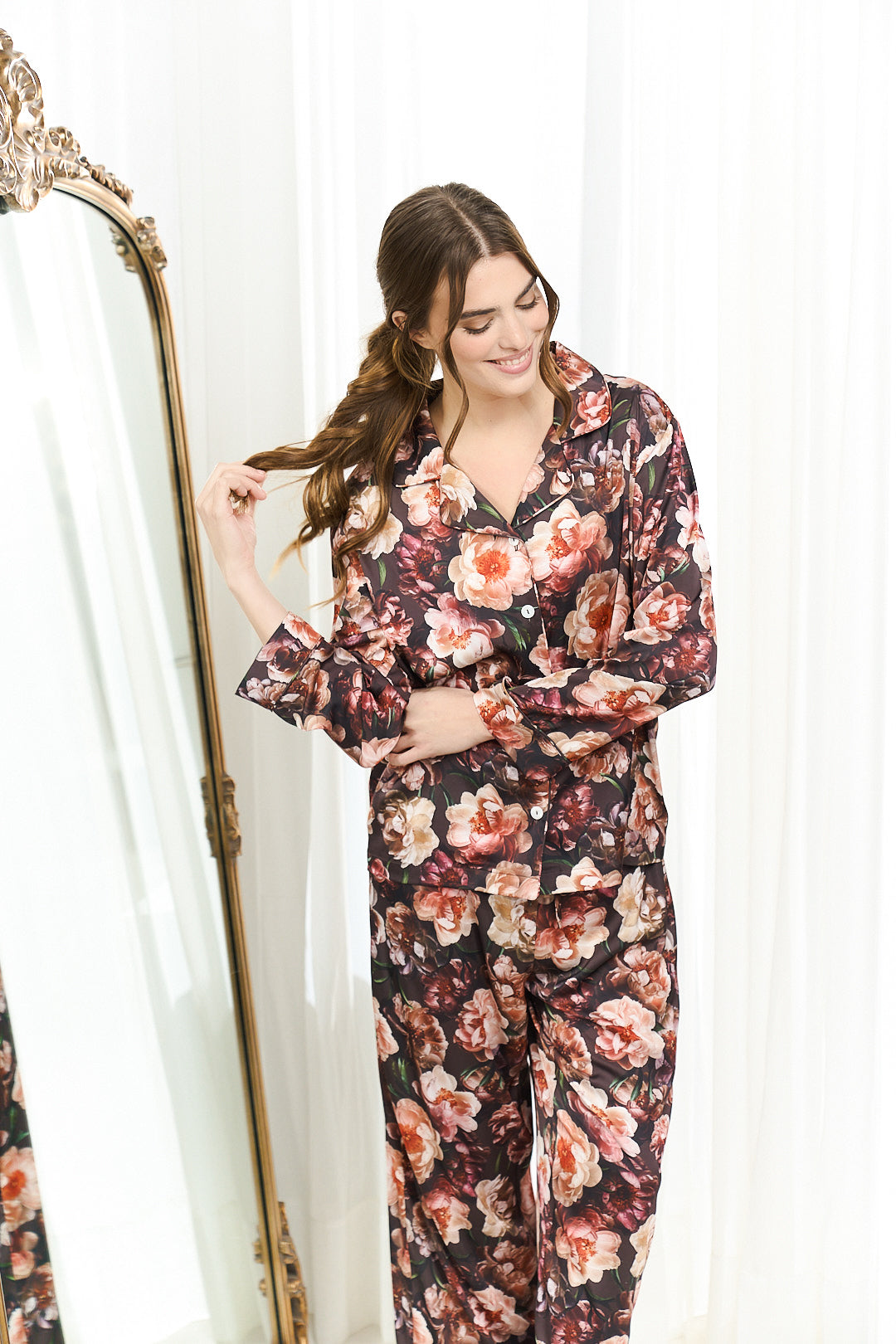 Woman wearing a By Catalfo Heavenly floral pajama set standing next to a mirror.