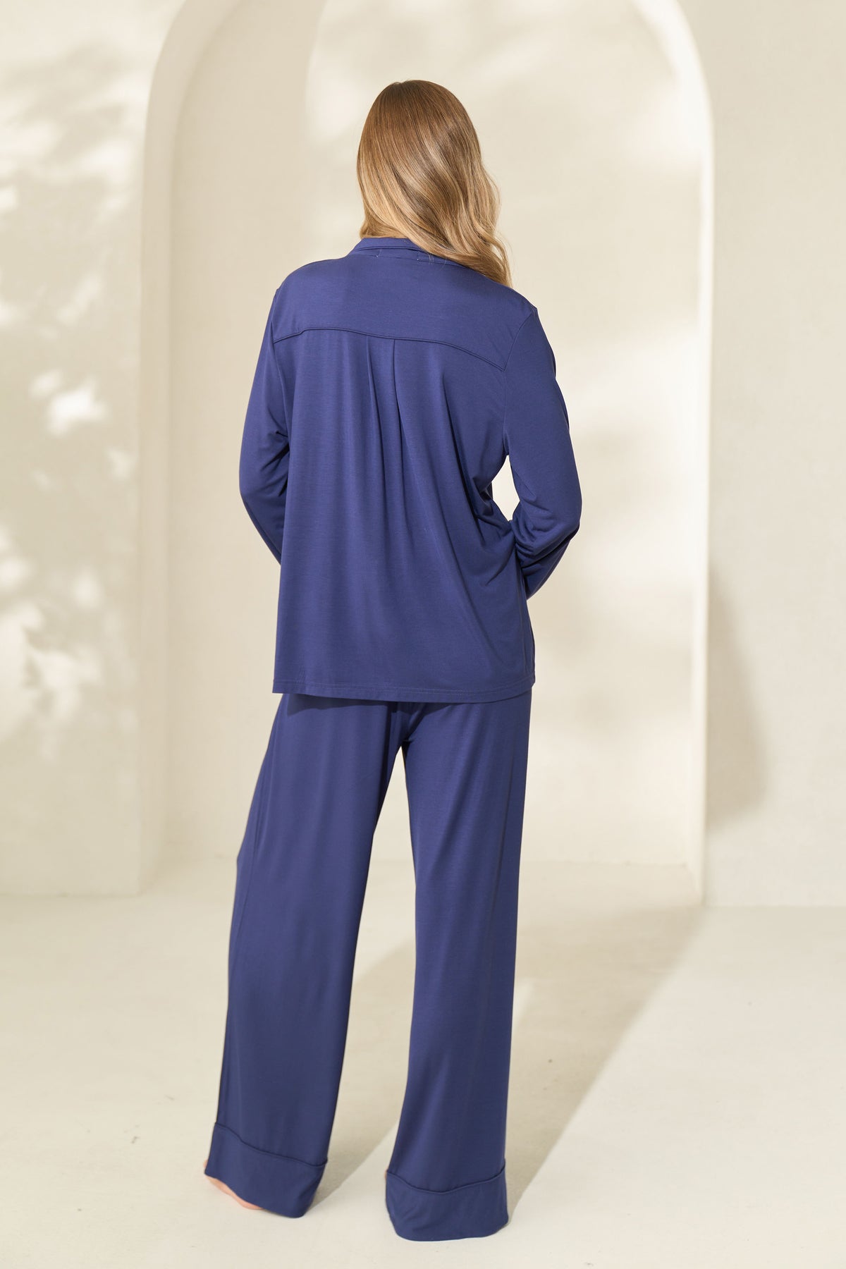 Back view of woman wearing long sleeve navy modal pajamas with elastic waistband