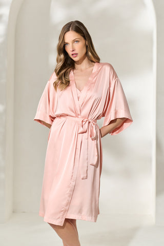 Woman posing wearing a knee length silky blush pink robe with waist tie