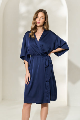 Woman wearing knee length silk-like navy robe with elegant sleeves and waist tie