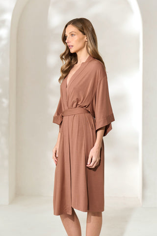 Side view of woman wearing brown knee-length modal robe with waist tie. 