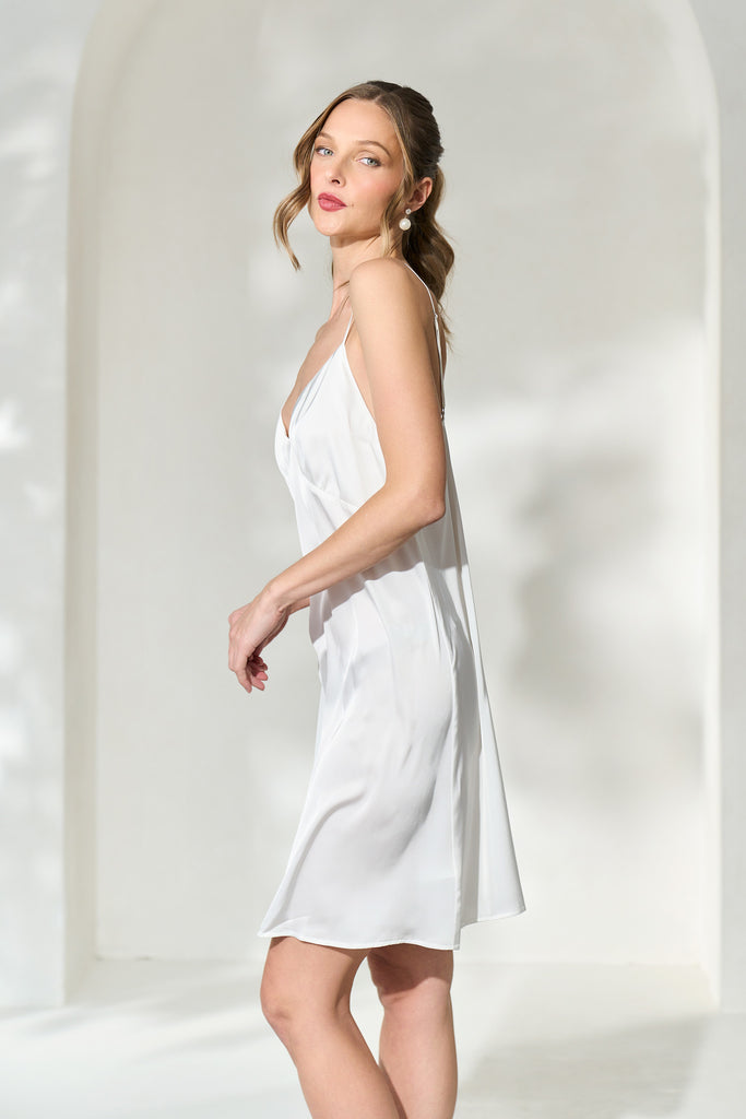 Side view of woman wearing knee length silky white slip dress