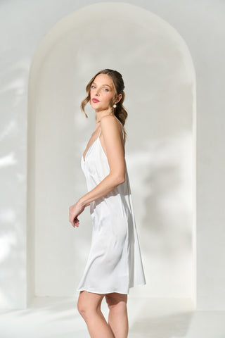 Side view of woman wearing knee length silky white slip dress