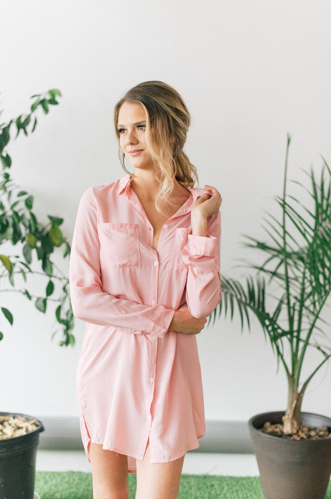 Woman adjusting collar of pink knee-length boyfriend shirt