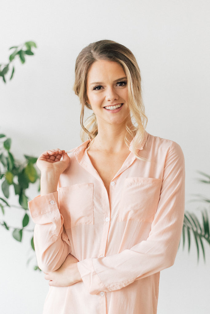 Smiling woman wearing peach colored boyfriend shirt