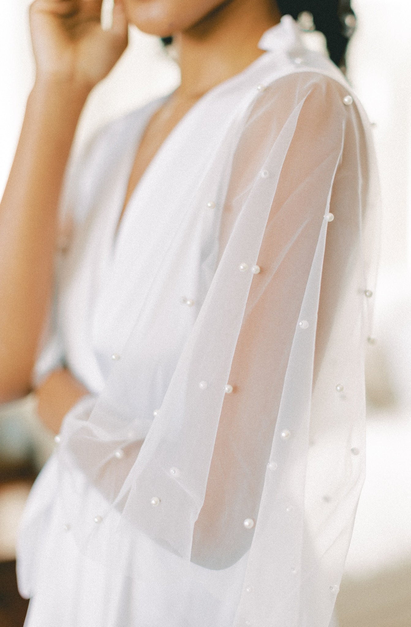 Close up view of pearl embellishments on the lace sleeves of a white bridal robe