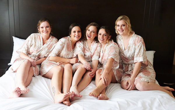bridesmaids on a bed getting-ready wearing by catalfo silk floral robes