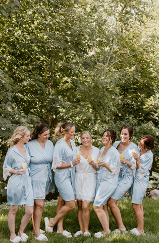 a bridal party celebrates on the wedding morning wearing silky light blue robes from By Catalfo