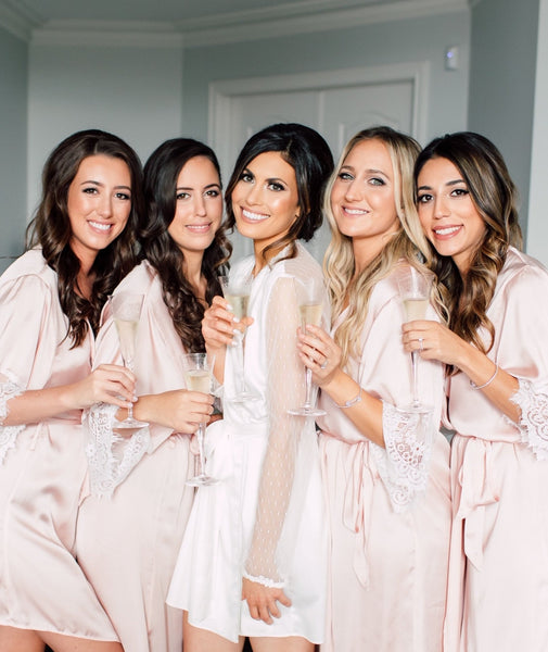 bridesmaids pictured together in blush silk robes with lace sleeves