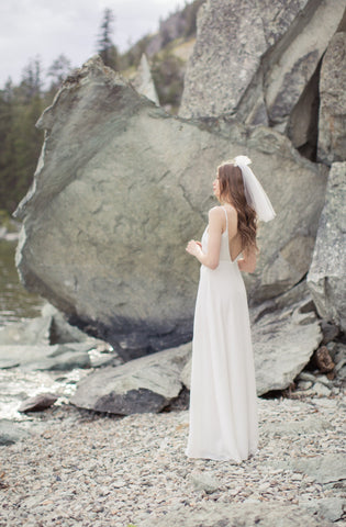 a bride poses on the West coast wearing open back, simple wedding dress