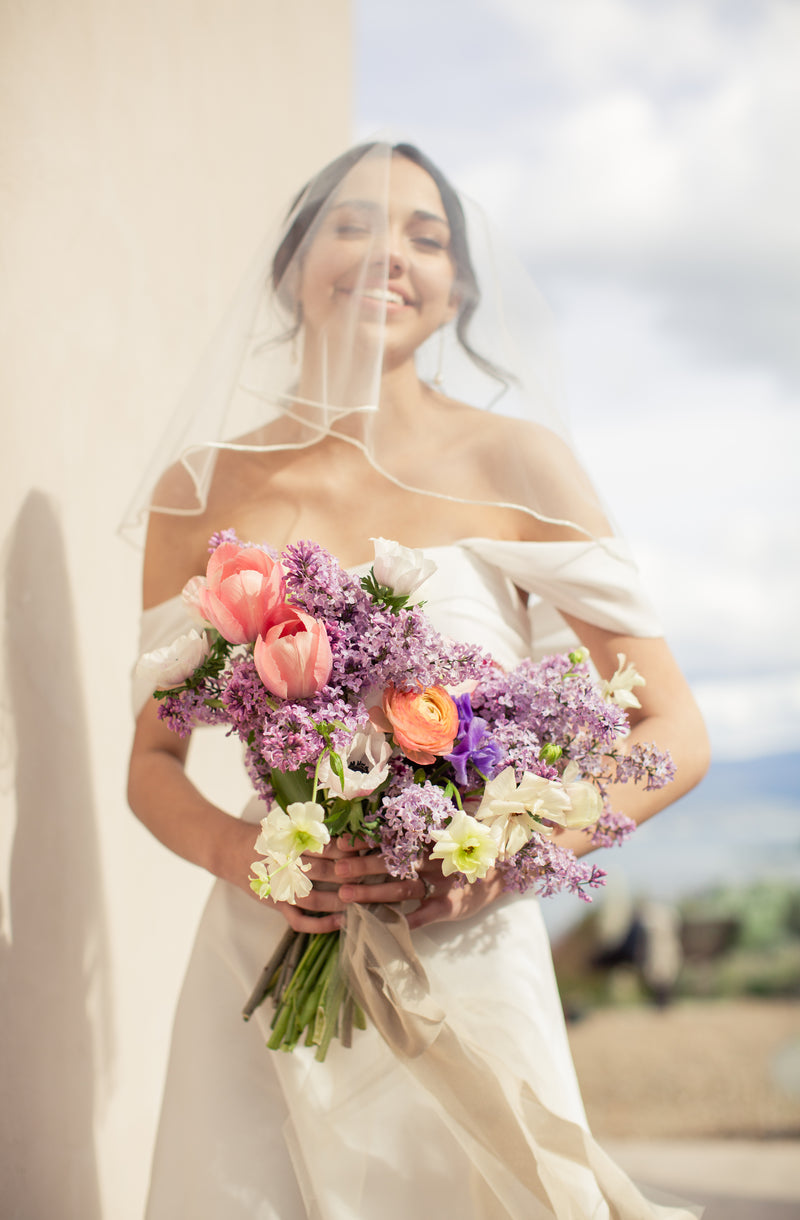 a bride poses with a colourful bouquet for Okanagan wedding