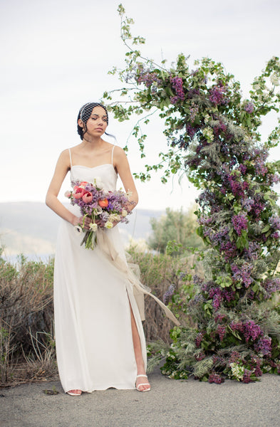 a bride wearing a simple and modern wedding dress with a colourful hand tied bouquet