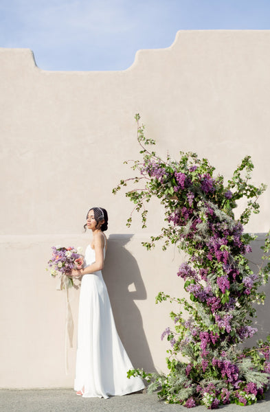 a bride poses with floral installation for intimate elopement wedding ceremony
