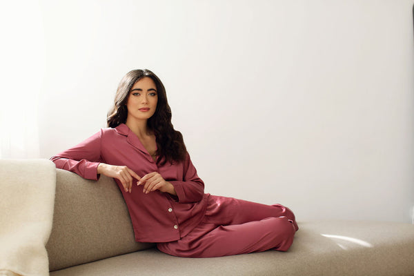 a women lounging at home wearing luxury, silky pajamas from By Catalfo in Toronto