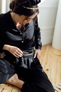 A model shows the fit of By Catalfo's black silky pyjama set for women 
