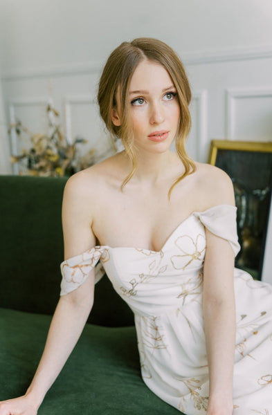 a model in  a white off-the-shoulder midi wedding dress