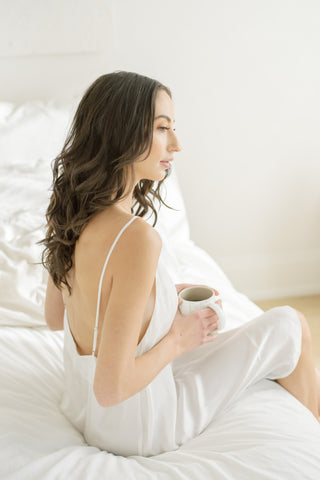 a women drinks coffee wearing simple white slip dress