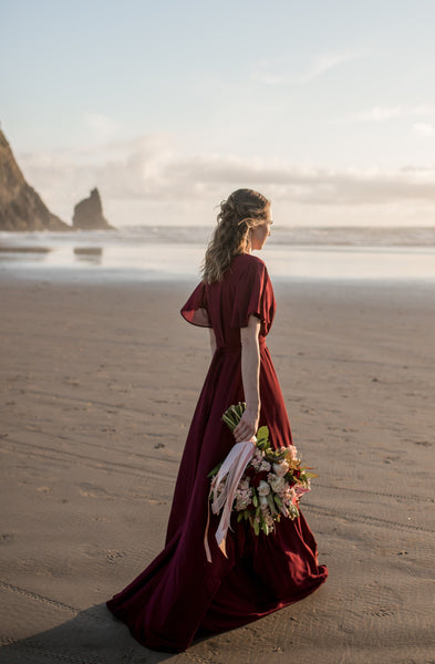 bridesmaid wearing a burgundy wrap dress at haystack rock, oregon