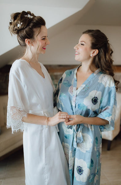 a bride poses with maid of honour, both wearing By Catalfo silk bridal robes