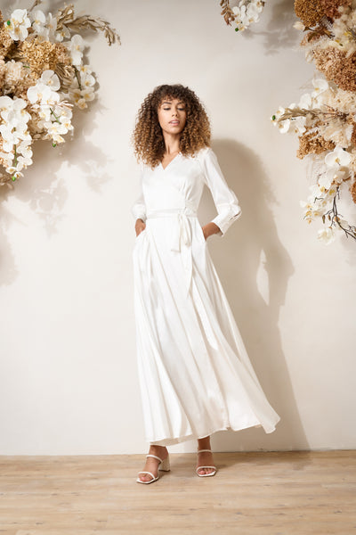 a model twirls wearing a flowy white wrap dress from By Catalfo